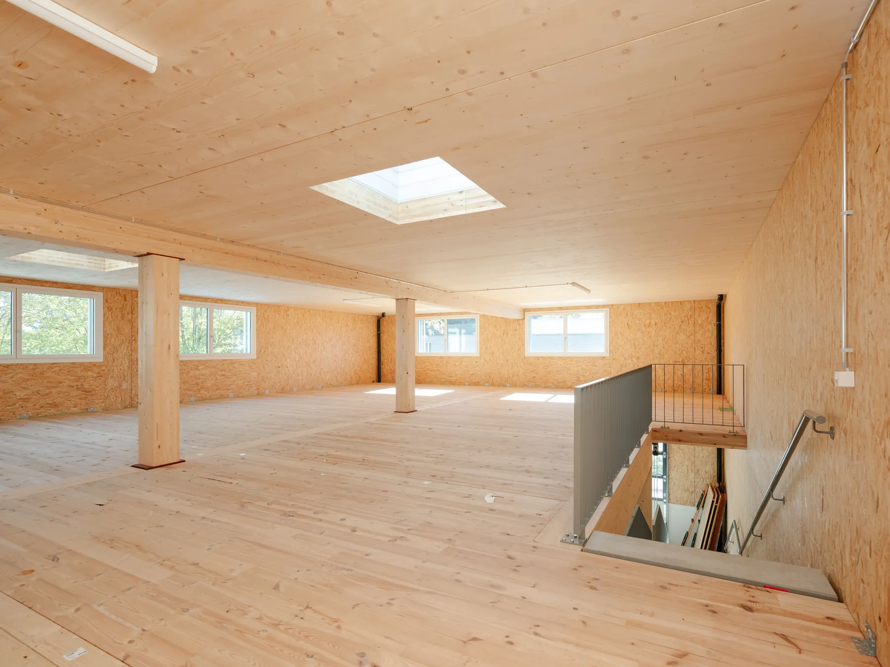 Obergeschoss mit sichtbarer Brettsperrholzdecke, Holzstützen und Oblicht