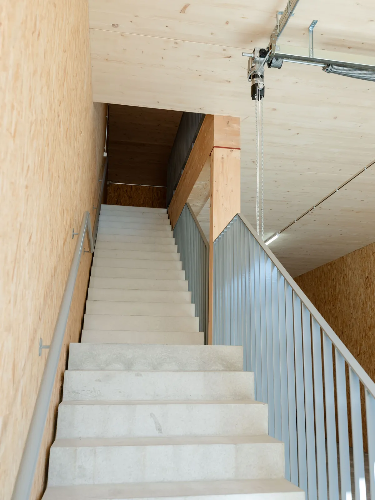 Betontreppe mit Stahlgeländer vor OSB-Wand